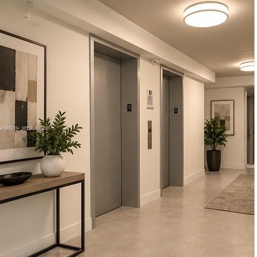 Dual elevator access featuring matte gray doors, recessed ceiling lighting, and large-format tile flooring