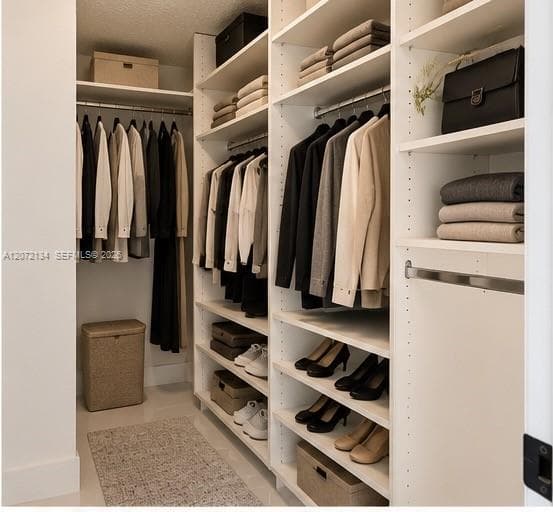Walk-in closet featuring white built-in shelving, multiple hanging rods, and adjustable vertical storage compartments