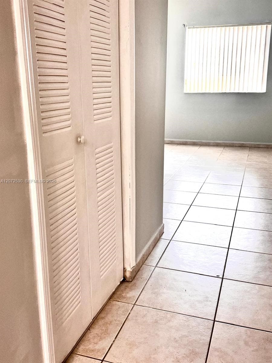 White louvered bifold doors and light-toned tile flooring