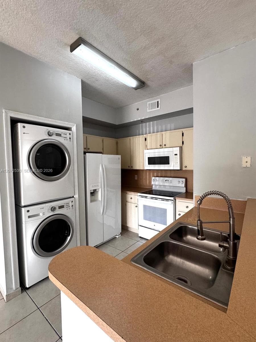 Kitchen area featuring wood-finish cabinetry, solid surface countertops, a stainless steel double-basin sink with a gooseneck faucet, and tiled flooring