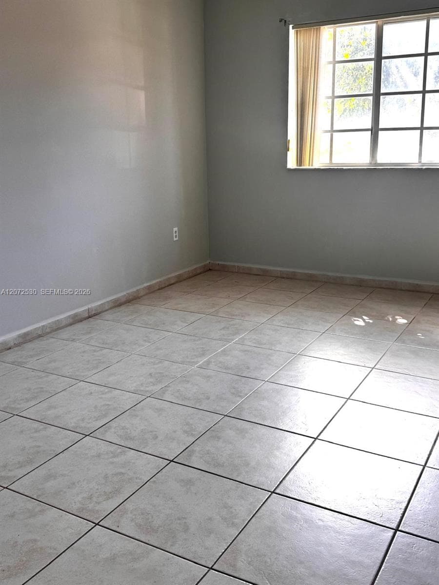 Neutral-toned wall finish, large-format square tile flooring, and multi-pane window with integral muntins
