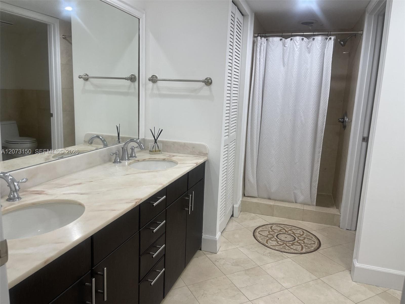 Vanity featuring a dark wood-finish cabinet, stone countertop with a matching backsplash, integrated oval sink, chrome widespread faucet, and full-width mirror