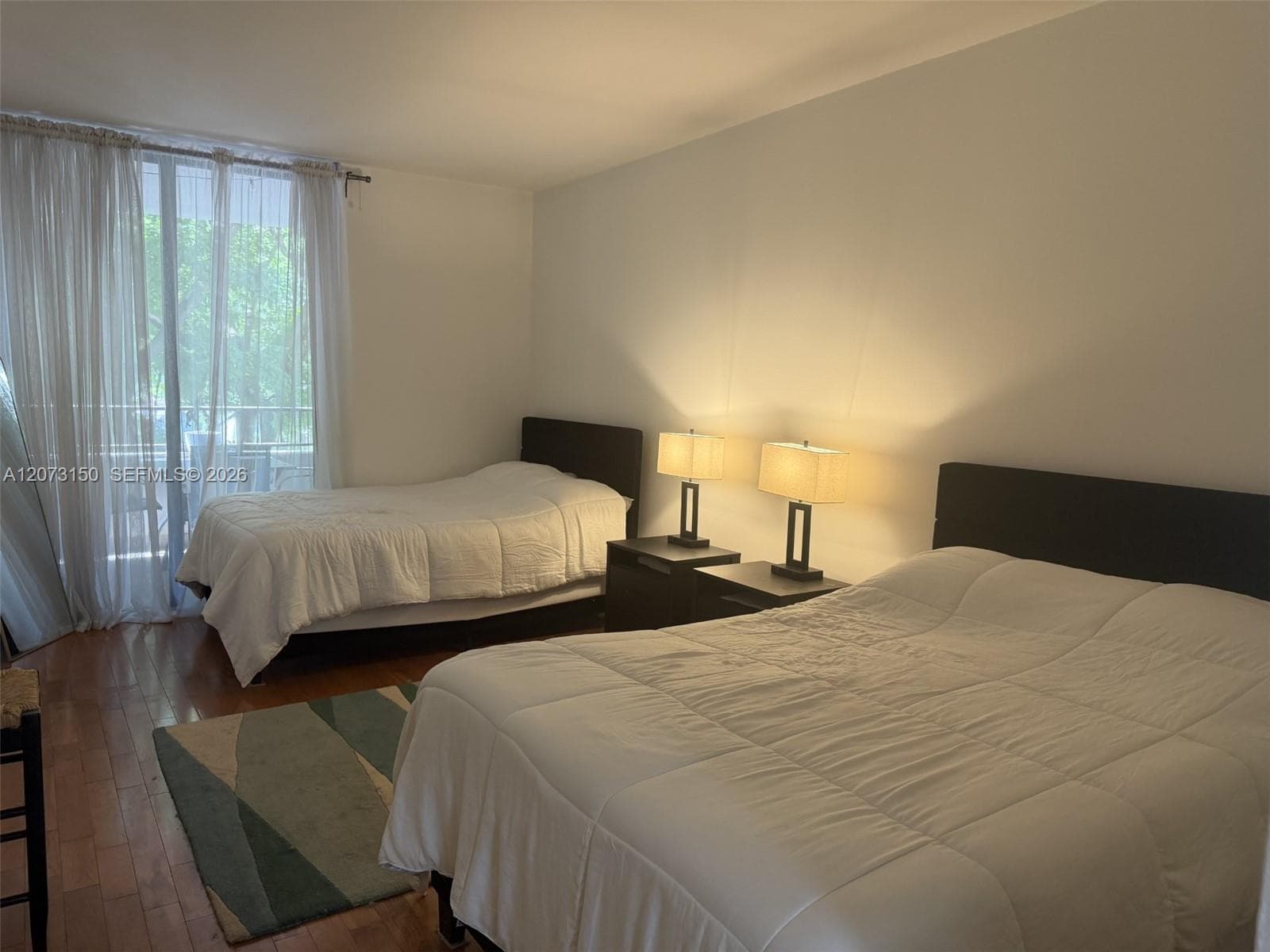 Hardwood flooring and floor-to-ceiling windows featuring metal curtain rods and sheer drapery