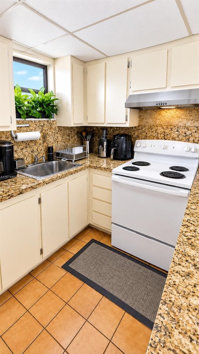 Kitchen featuring stone-finish countertops, tile flooring, white cabinetry, a stainless steel undermount sink, and an integrated stainless steel range hood