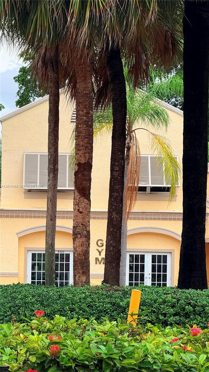 Stucco exterior featuring dual-entry glass panel doors, arched recessed entries, and exterior shutters