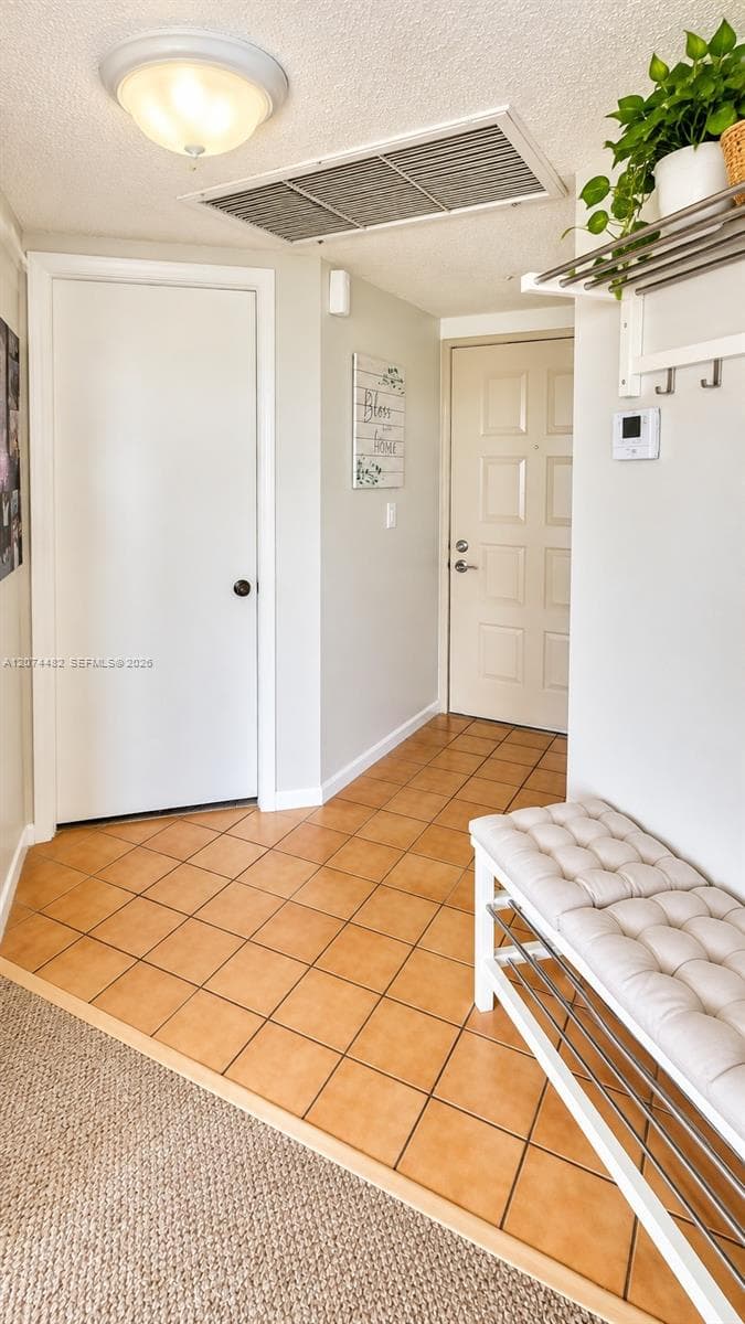 Entryway featuring ceramic tile flooring, a multi-panel door, and a wall-mounted metal coat rack