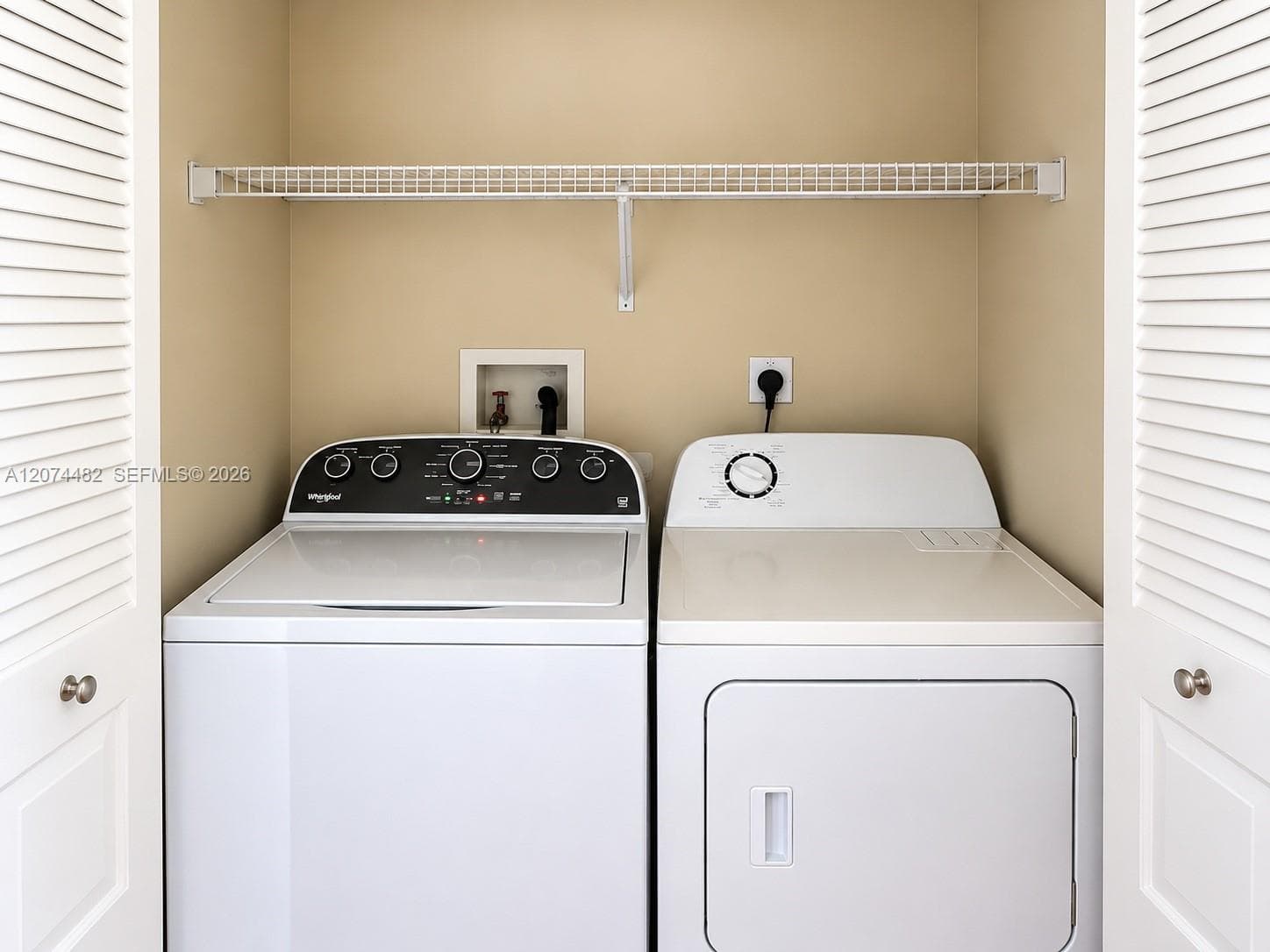 Laundry closet featuring white louvered bifold doors and a built-in wire shelving unit
