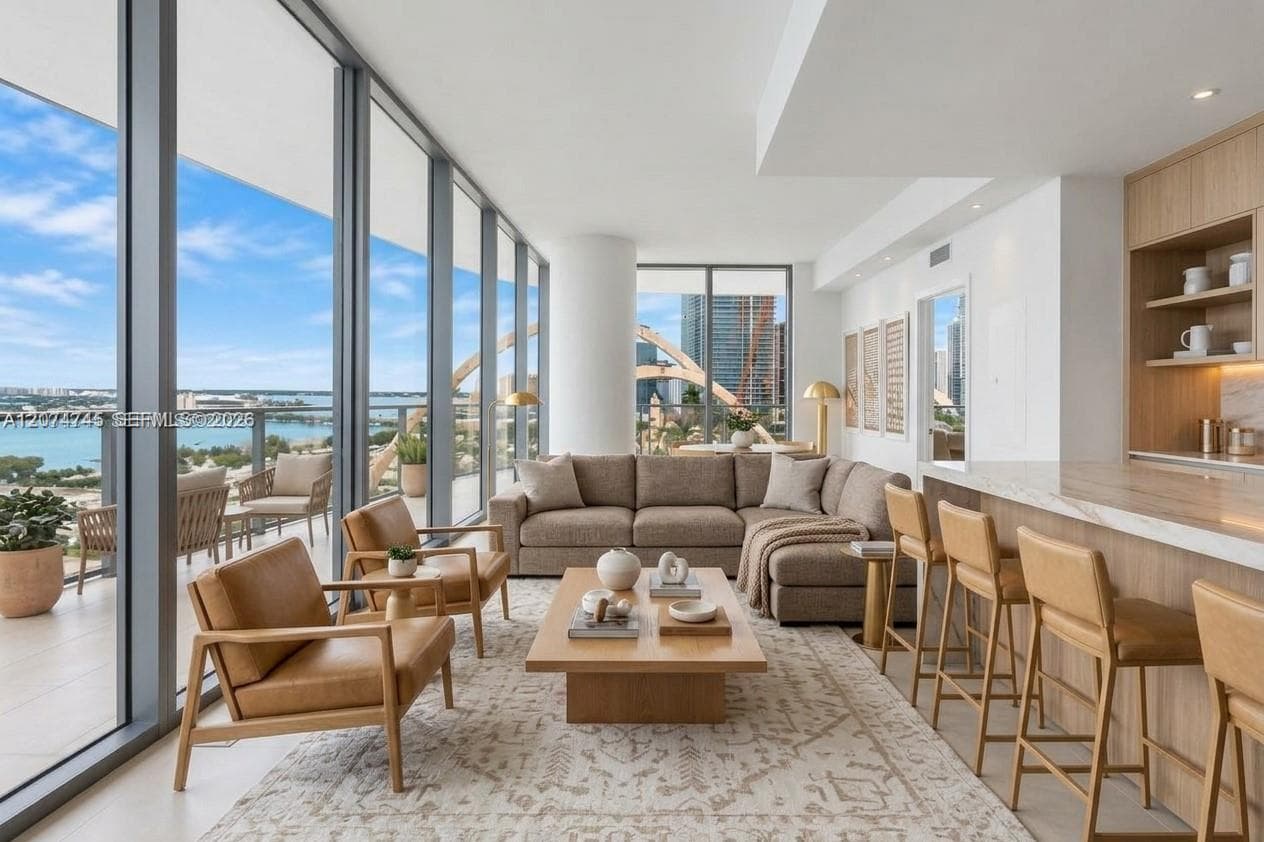 Floor-to-ceiling glass walls, expansive balcony, light wood cabinetry, stone-surfaced kitchen island, and recessed lighting