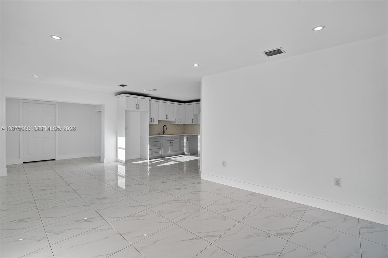 Open floor plan featuring large-format stone-finish tile flooring, recessed lighting, and crisp white walls