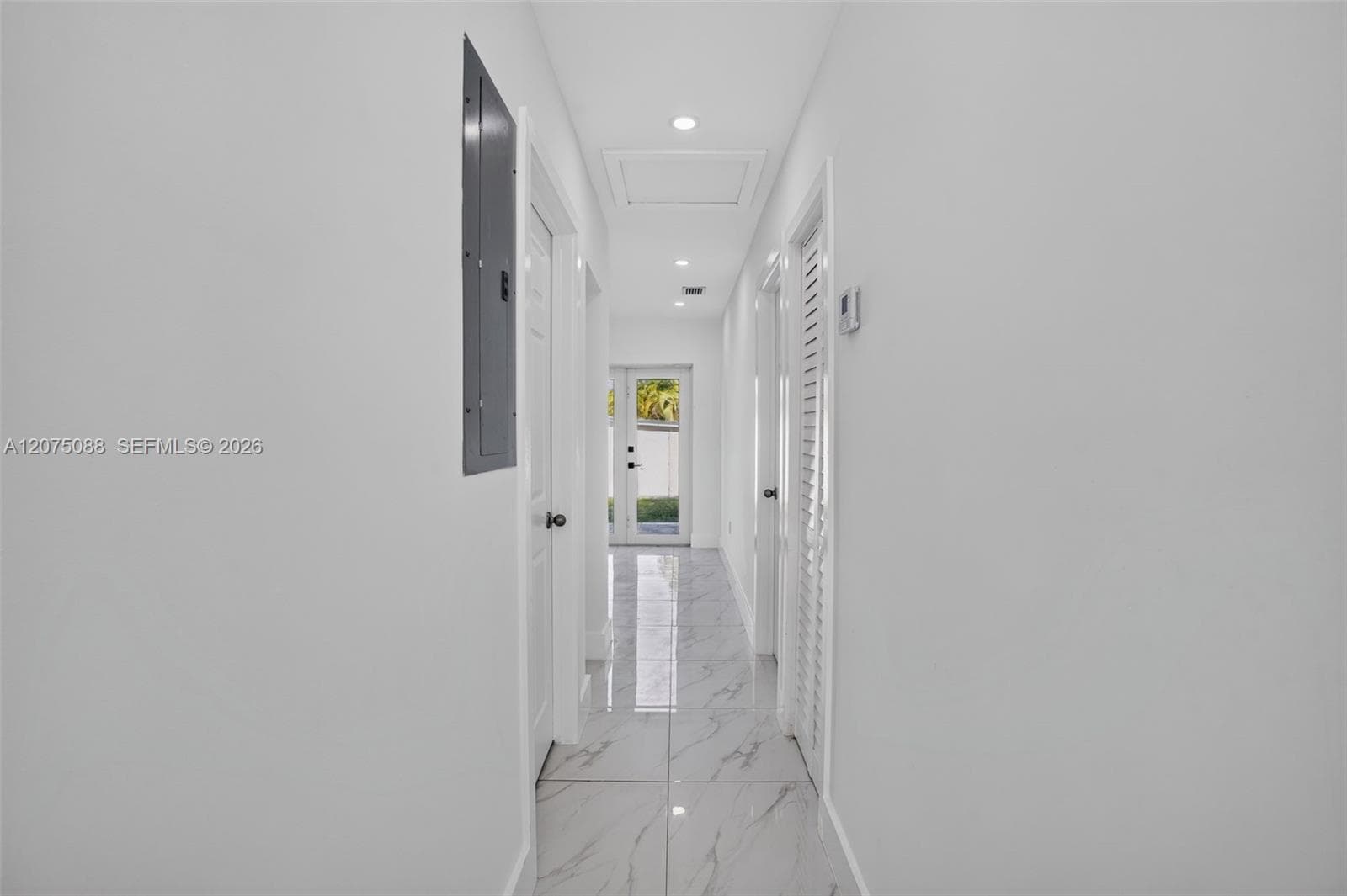 Interior hallway featuring light-toned stone-finish tile flooring, recessed lighting, and dual-panel interior doors