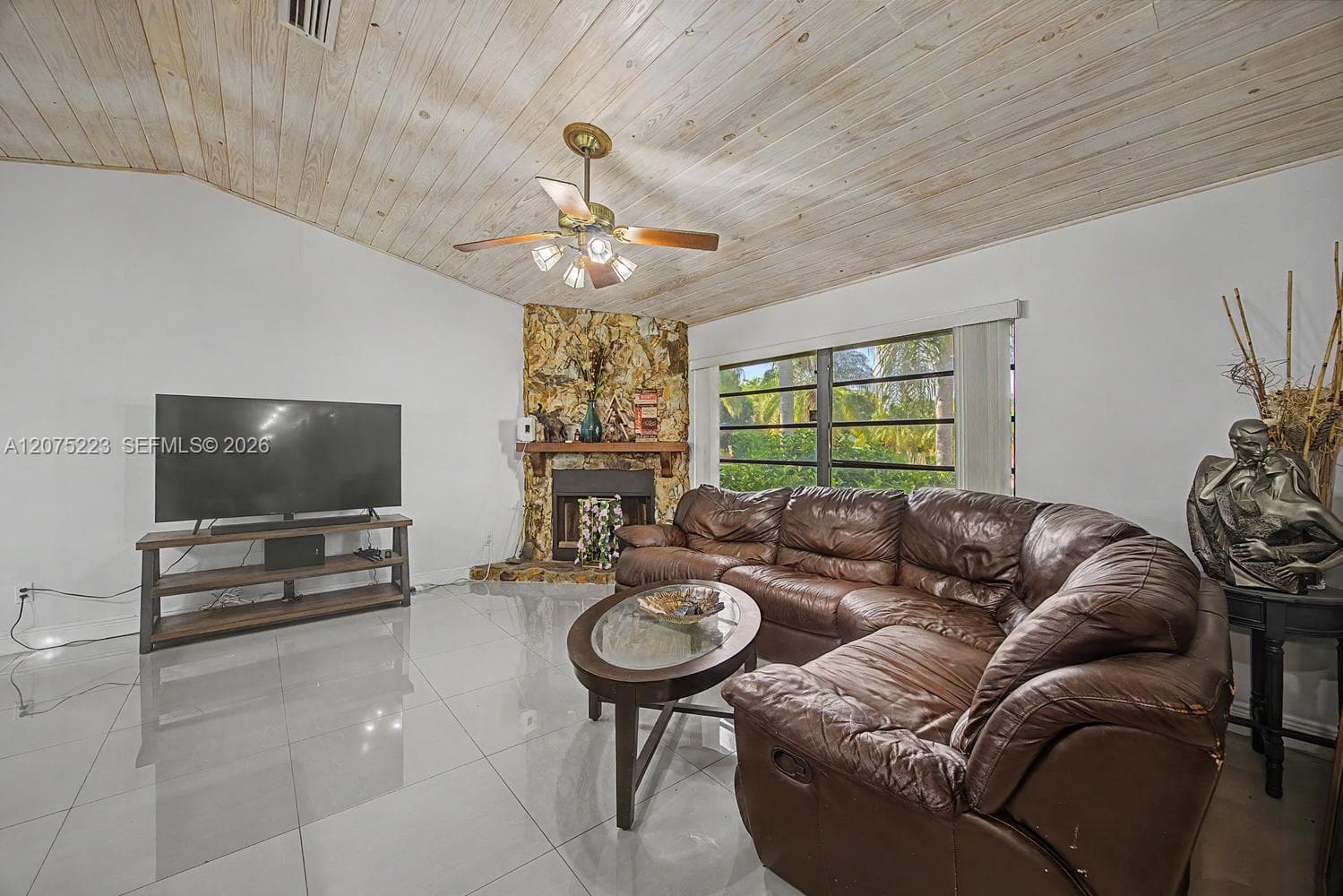 Spacious living room with vaulted ceilings, large windows and an eye-catching stone fireplace.