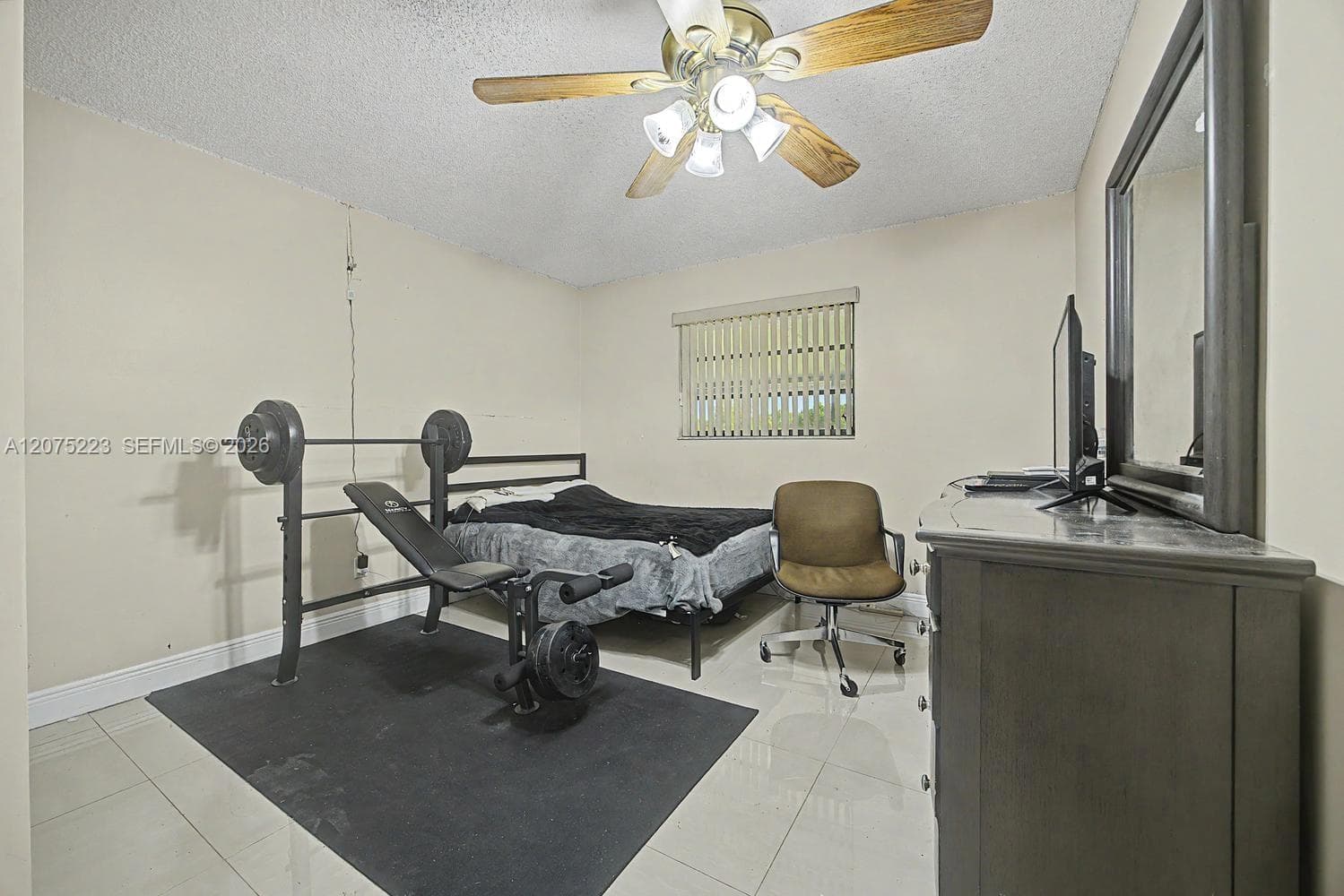 Comfortable secondary bedroom 1 with tile flooring, ceiling fan and natural light.