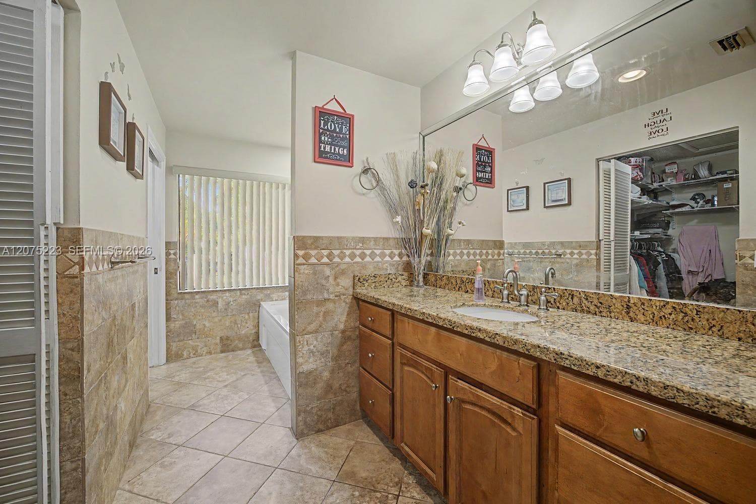 Spacious primary bath with granite-topped vanity, generous storage and tiled finishes throughout.