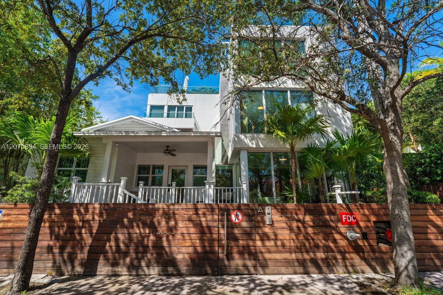 Contemporary façade surrounded by tropical landscaping — boutique Miami Beach townhouse near the ocean and parks.