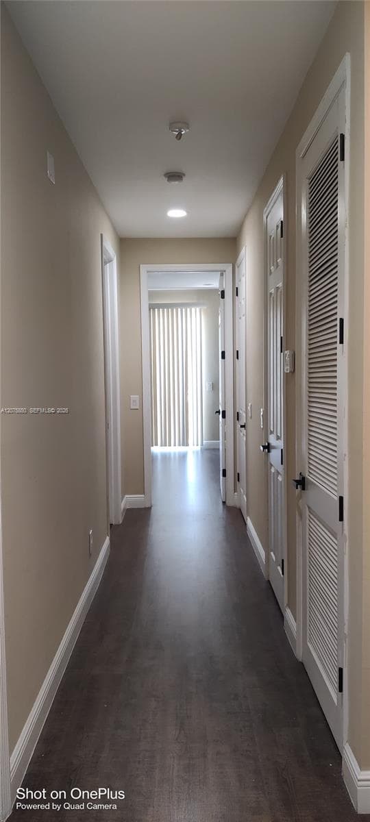 Hallway featuring wood-finish flooring, recessed lighting, and multiple interior doors with louvered closet accents