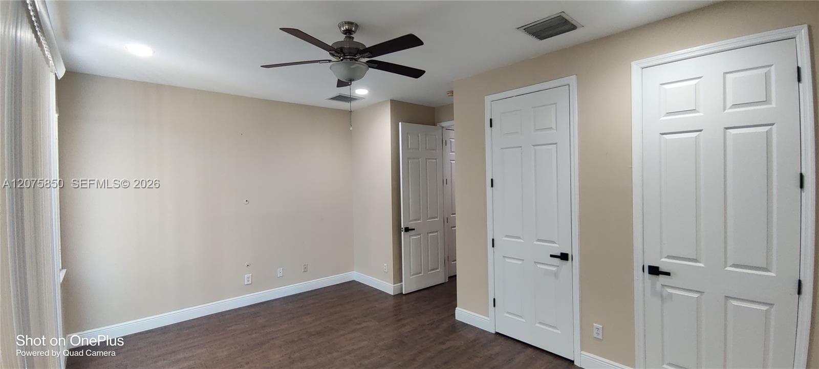 Wood-finish flooring, multi-panel doors with matte black hardware, recessed ceiling lighting, and a multi-blade ceiling fan