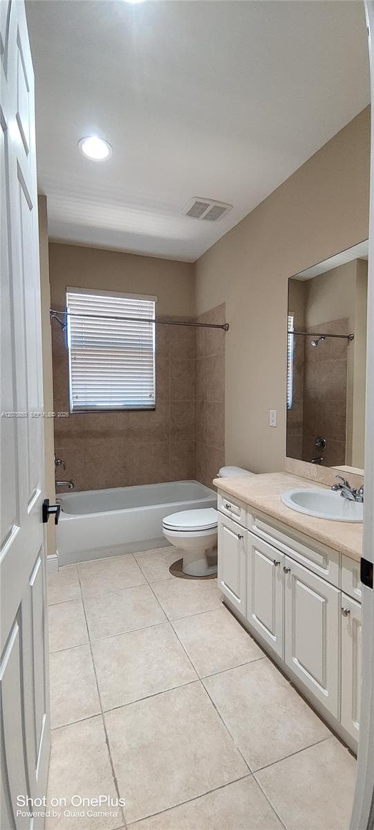 Bathroom featuring white cabinetry, solid surface countertop with an integrated sink, tiled flooring, and a tub-shower combination with full-height tile surround