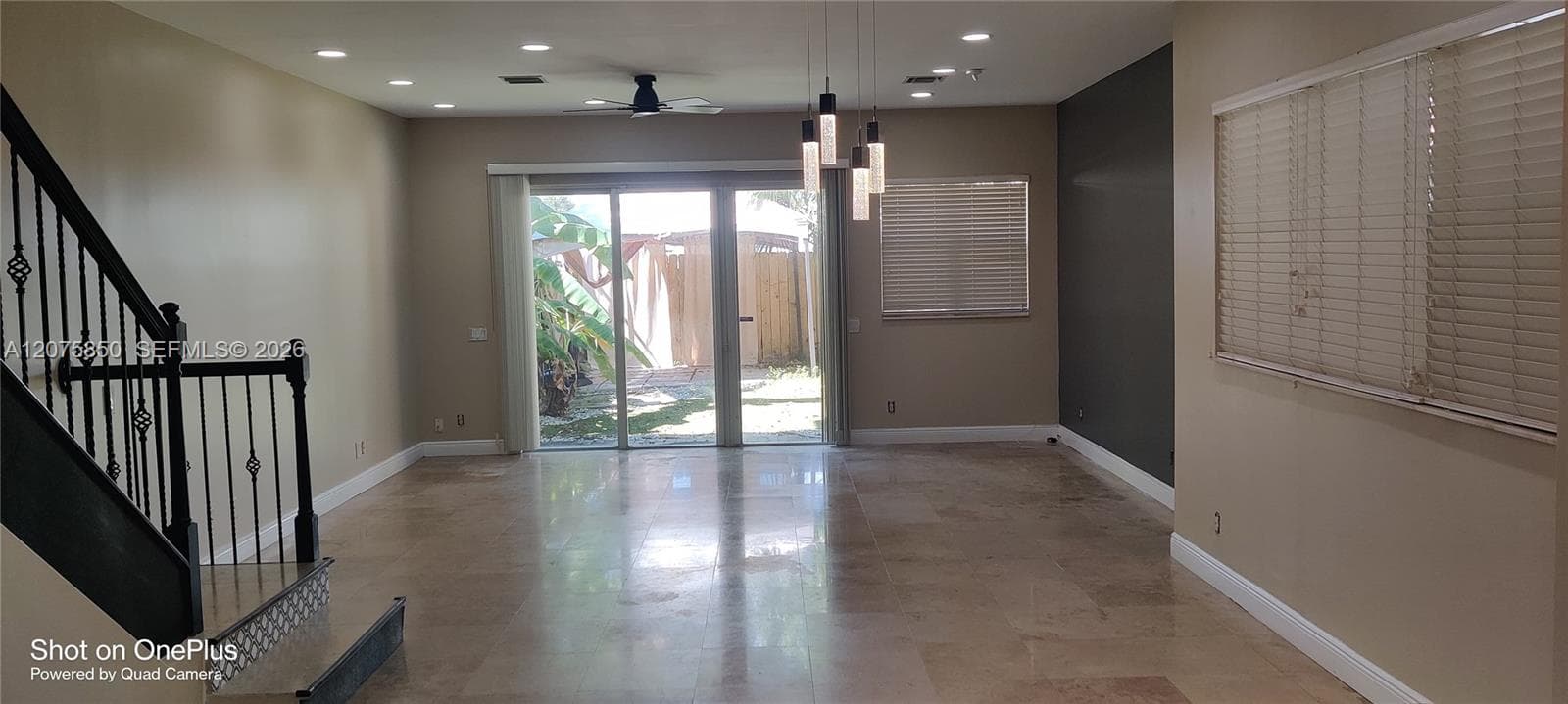 Polished stone flooring, glass sliding doors, recessed ceiling lighting, multi-pendant light fixture, and a staircase with an iron-spindle railing