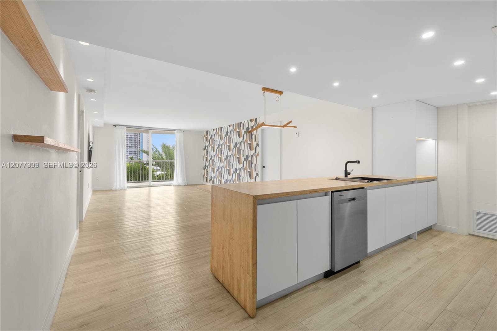 Kitchen featuring wood-finish cabinetry, waterfall island with a matte black faucet, wood-finish flooring, recessed lighting, and floating shelves