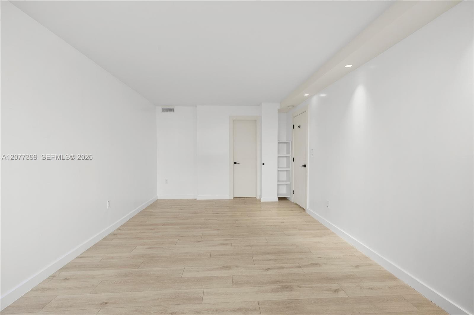 Neutral interior featuring wood-finish flooring, recessed lighting, and built-in shelving