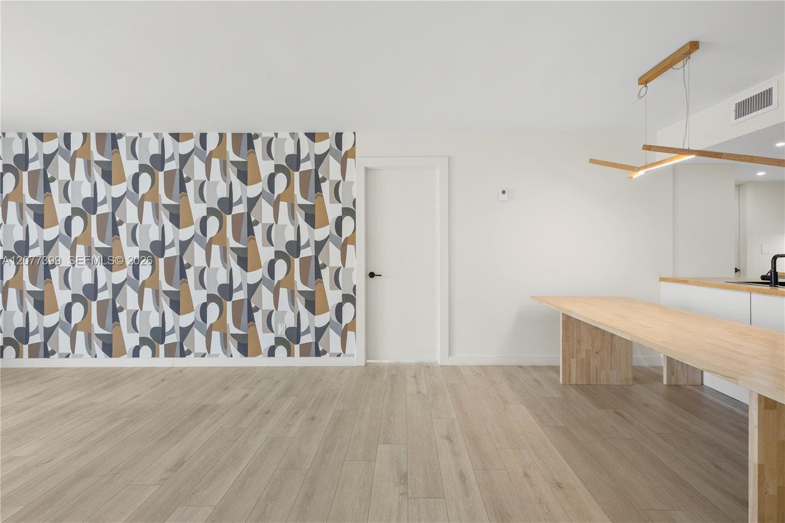 Geometric pattern accent wall, wood-finish flooring, and minimalist linear wood-finish pendant lighting