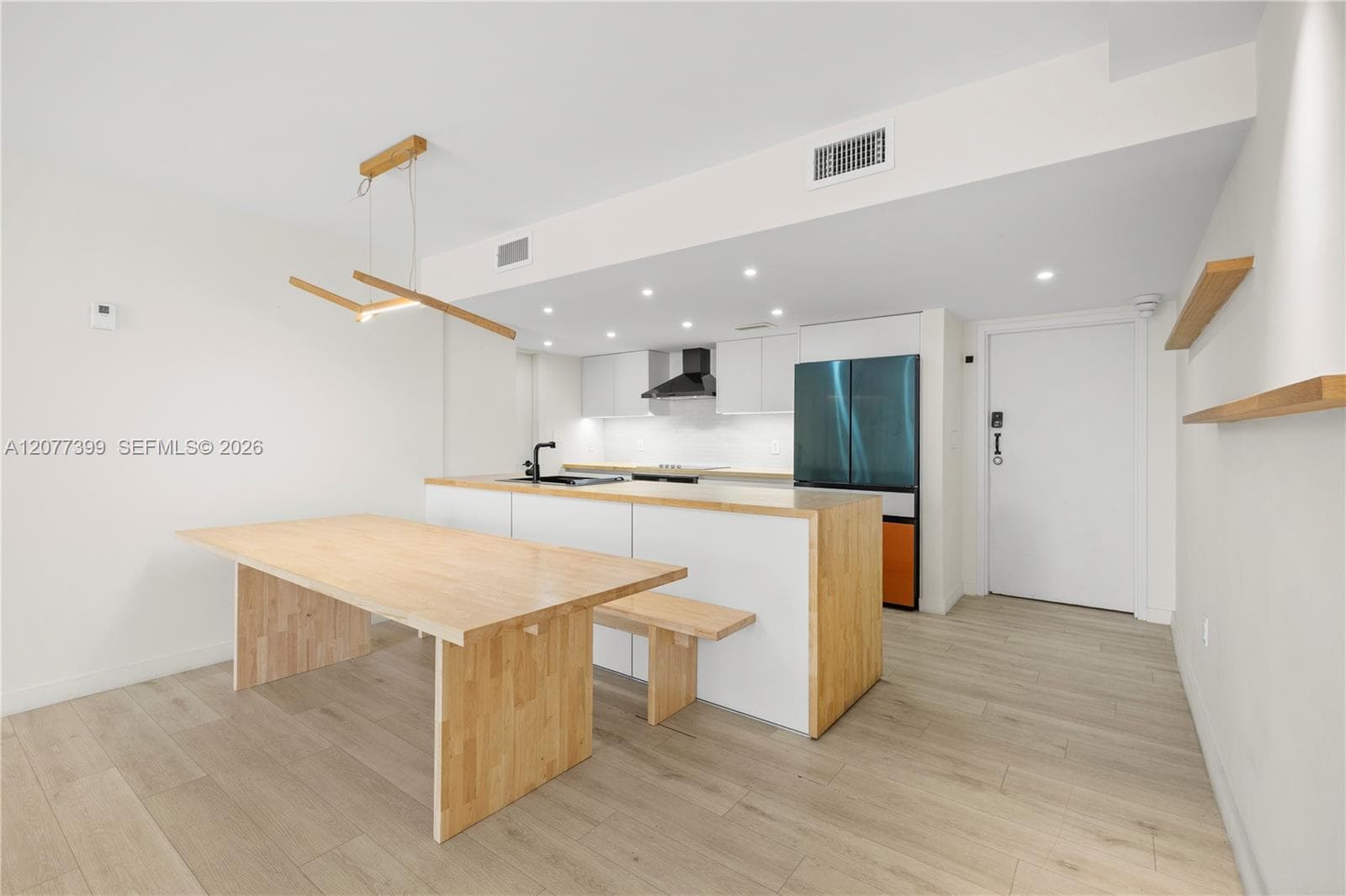 Kitchen featuring white flat-panel cabinetry, wood-finish countertops, matte black plumbing fixtures, recessed lighting, and wood-finish flooring