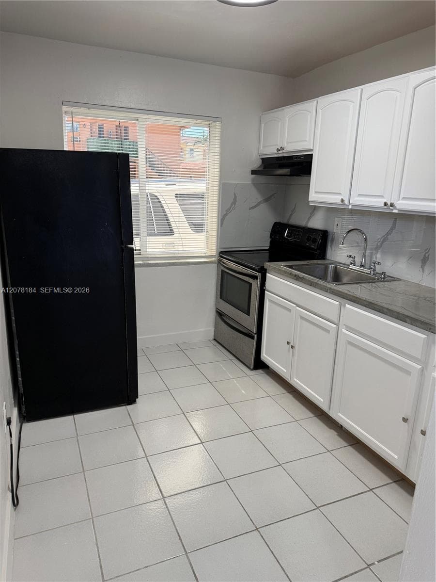 Kitchen featuring white shaker-style cabinetry, stone-finish countertops, tile flooring, and stainless steel range