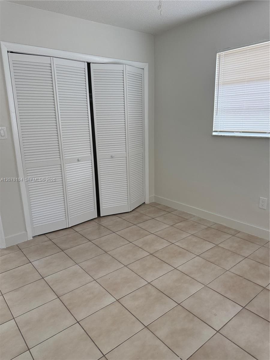 Neutral wall tones, ceramic tile flooring, and bi-fold louvered closet doors