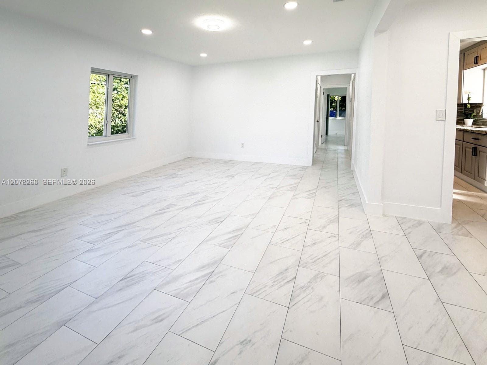 Neutral-toned interior featuring rectified porcelain tile flooring, recessed LED lighting, and white walls