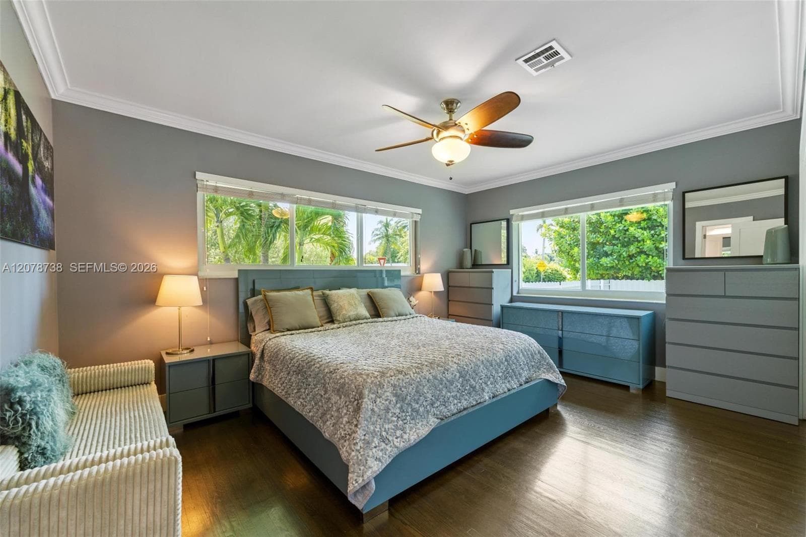 Leaving the shared spaces behind, the primary bedroom introduces a quieter mood with soft tones, warm floors, and abundant natural light.
