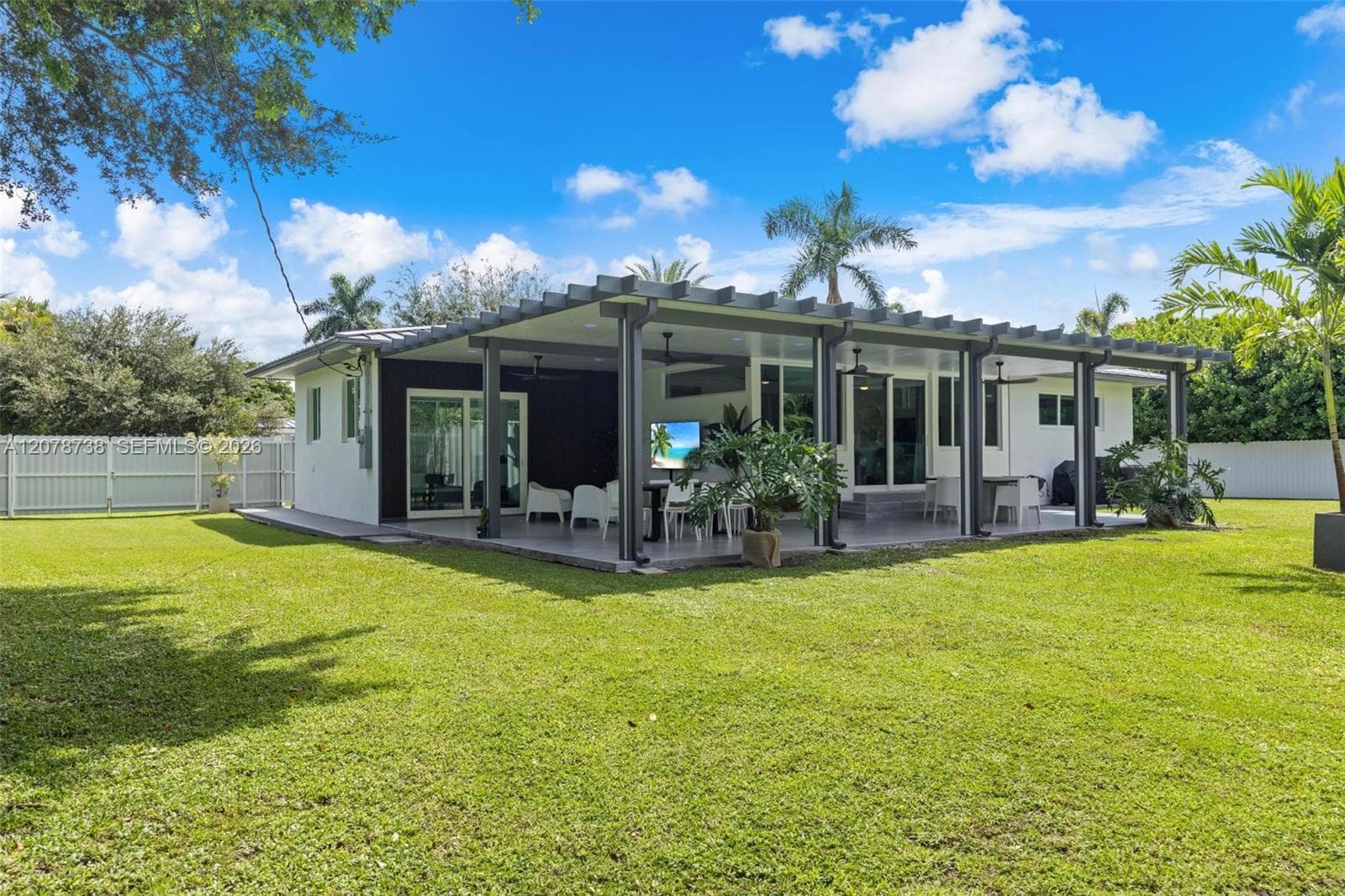 Large windows frame the mature landscaping, while the covered front porch and tropical surroundings give the property the relaxed indoor-outdoor character that makes South Miami living so special.