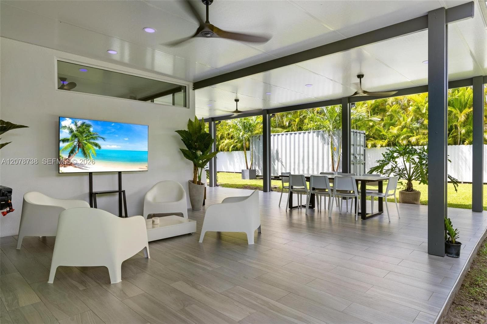 Beyond the main entertaining spaces, the home transitions into a bright secondary living area surrounded by windows and views of the greenery outside.
