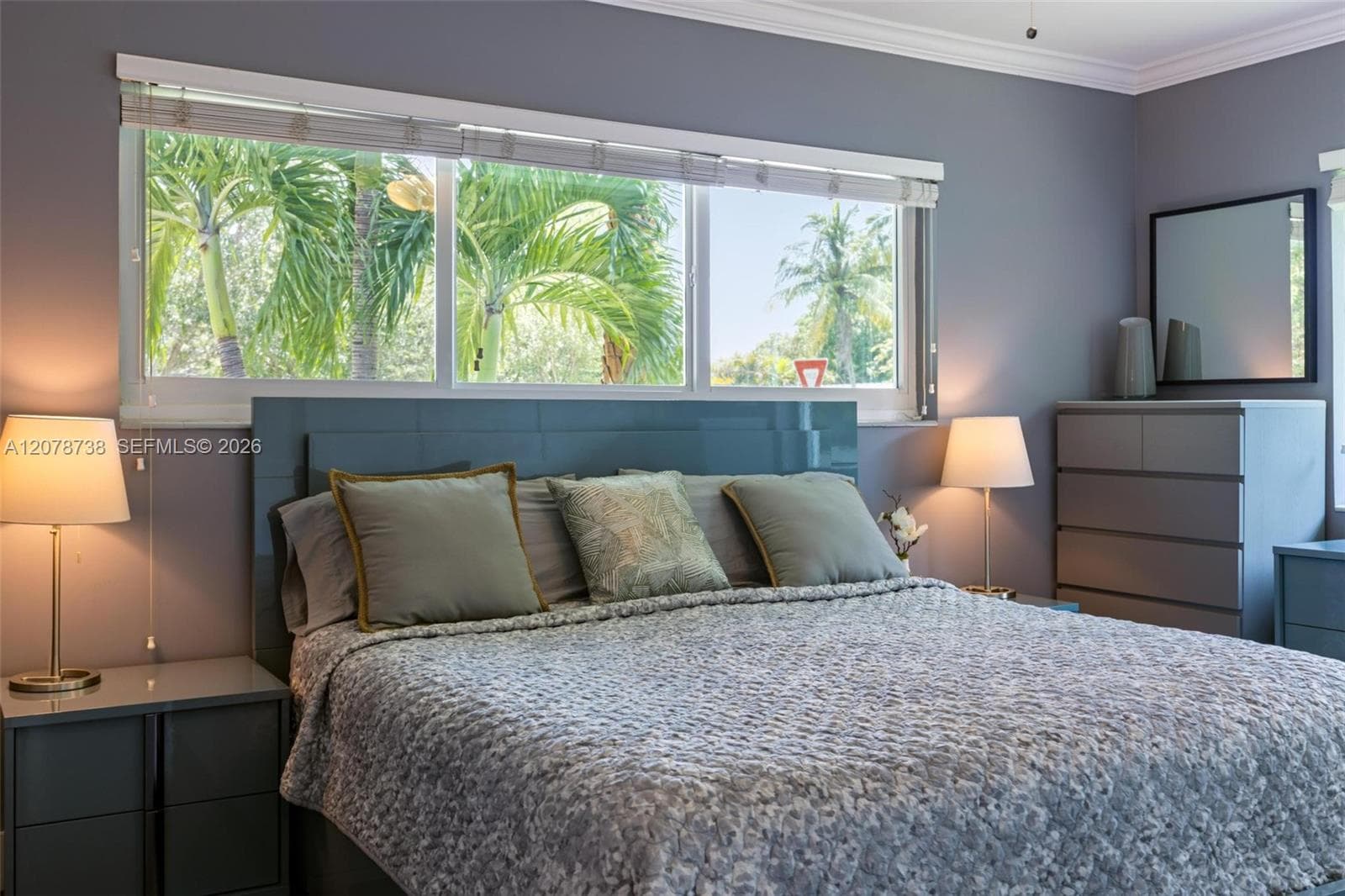 A wall of windows frames tropical greenery, bringing a distinctly Miami backdrop into the bedroom.