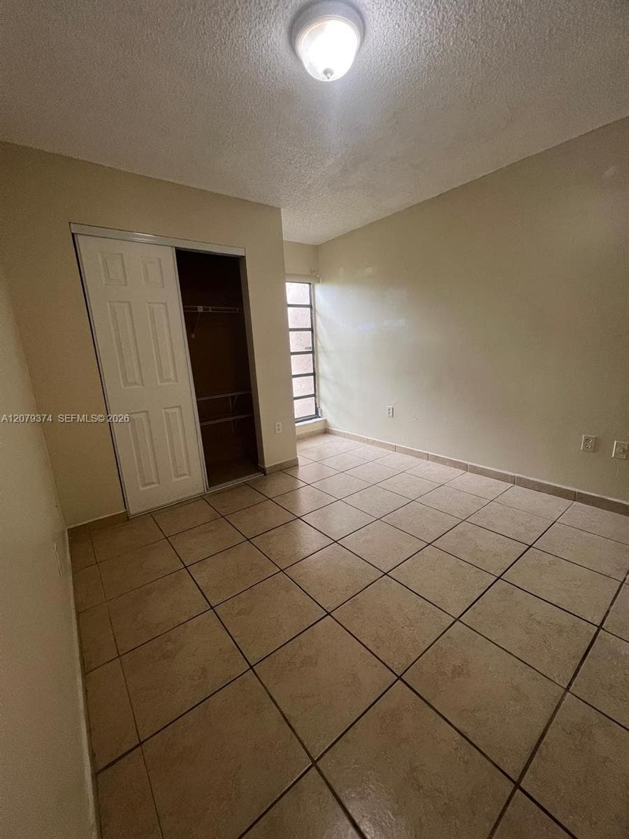 Ceramic tile flooring, sliding closet door with multi-panel detail, and a multi-pane vertical window