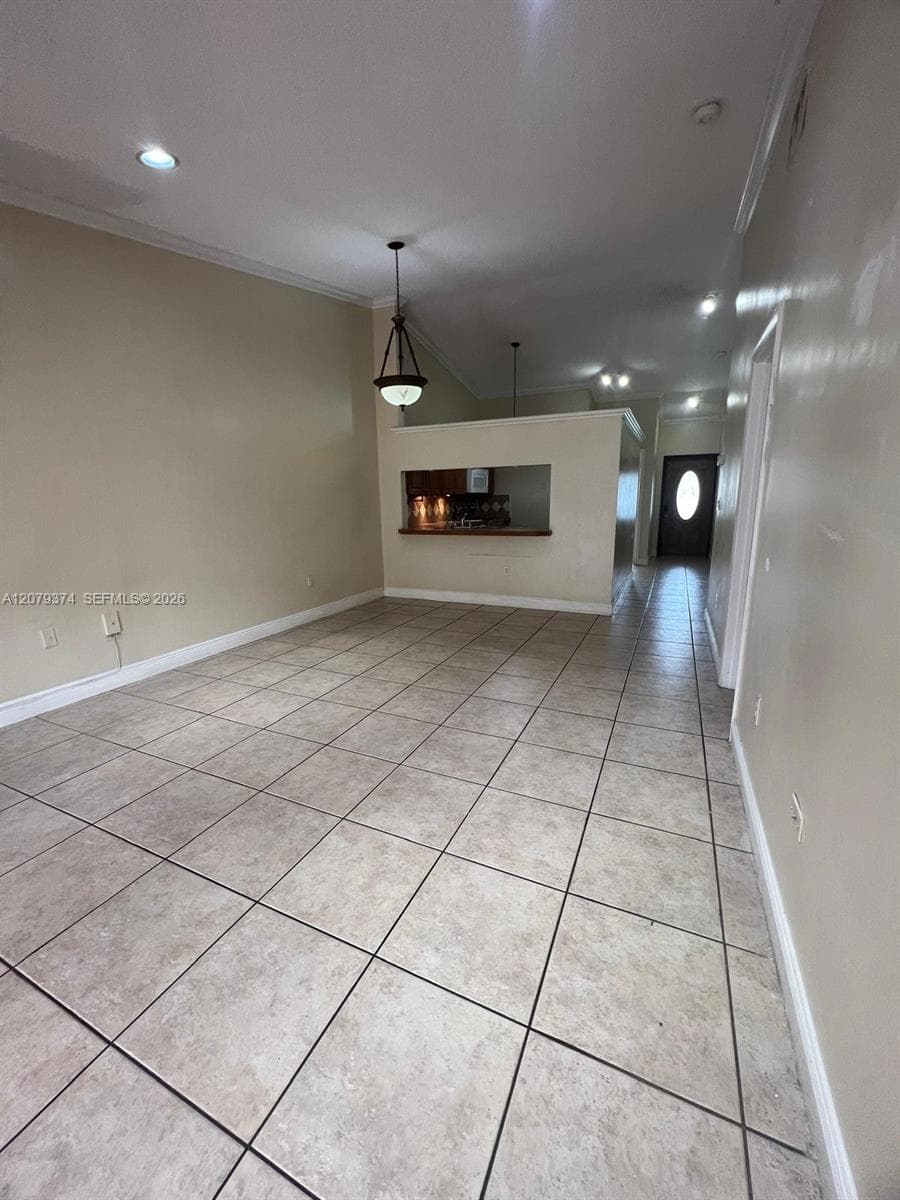 Ceramic tile flooring, vaulted ceilings, recessed lighting, decorative pendant fixture, and interior pass-through window with a ledge