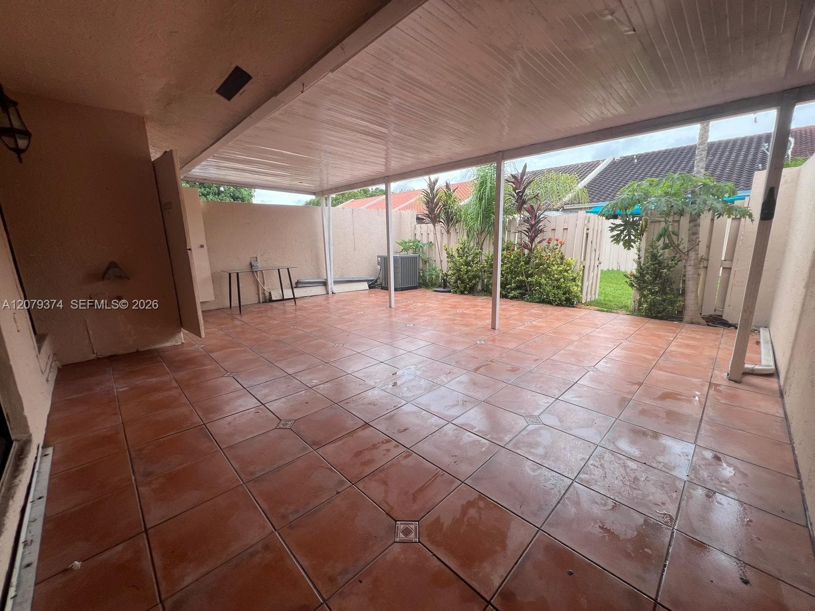 Covered patio featuring ceramic tile flooring, a solid support beam structure, and a fenced exterior boundary