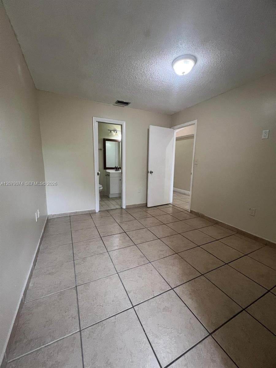 Interior room featuring large-format ceramic tile flooring, neutral wall tones, and overhead lighting
