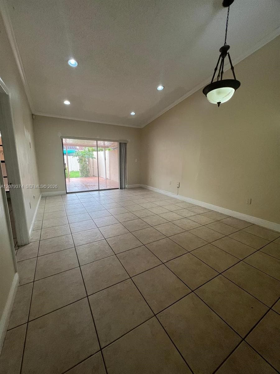 Vaulted ceilings, large-format tile flooring, recessed lighting, bronze-finish pendant lighting, and sliding glass doors to the exterior