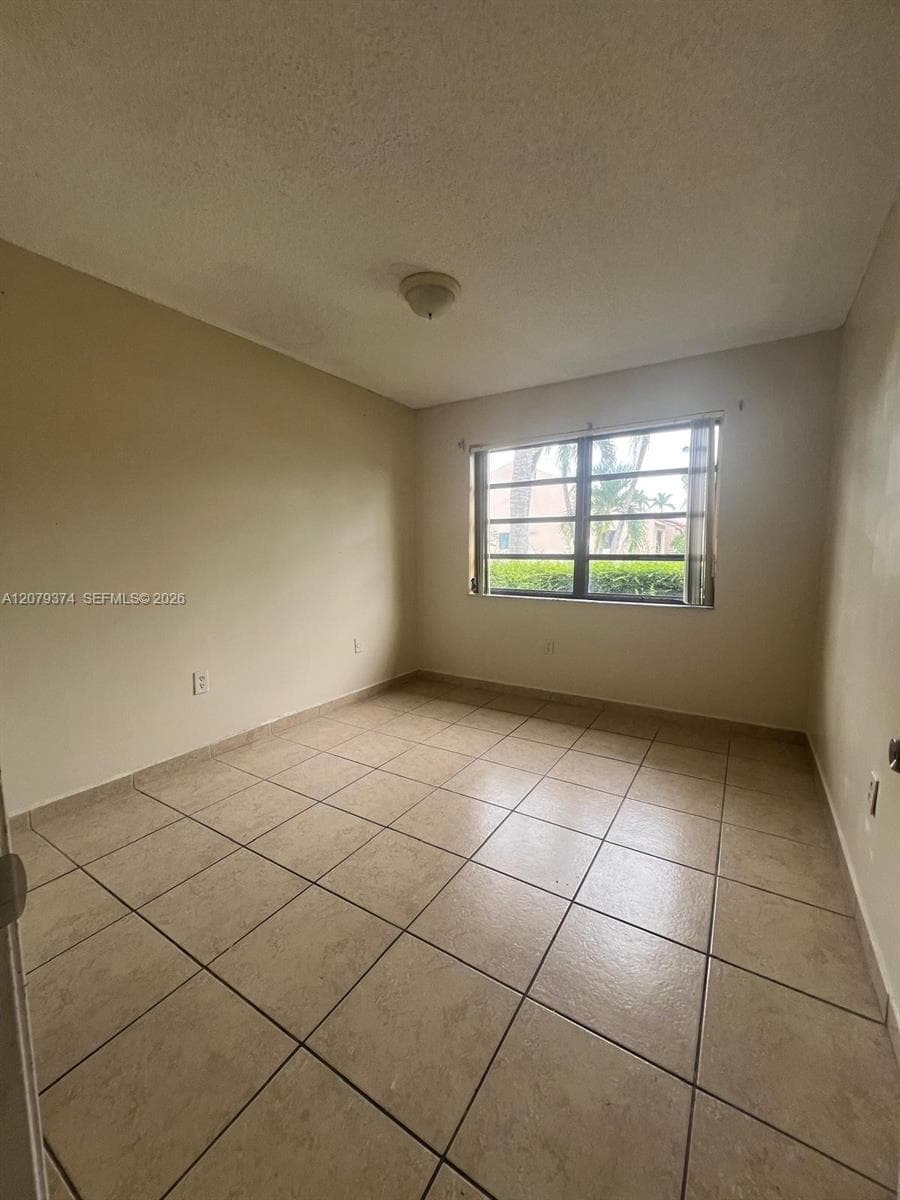 Neutral-toned interior space featuring light-colored square tile flooring and a multi-pane horizontal window
