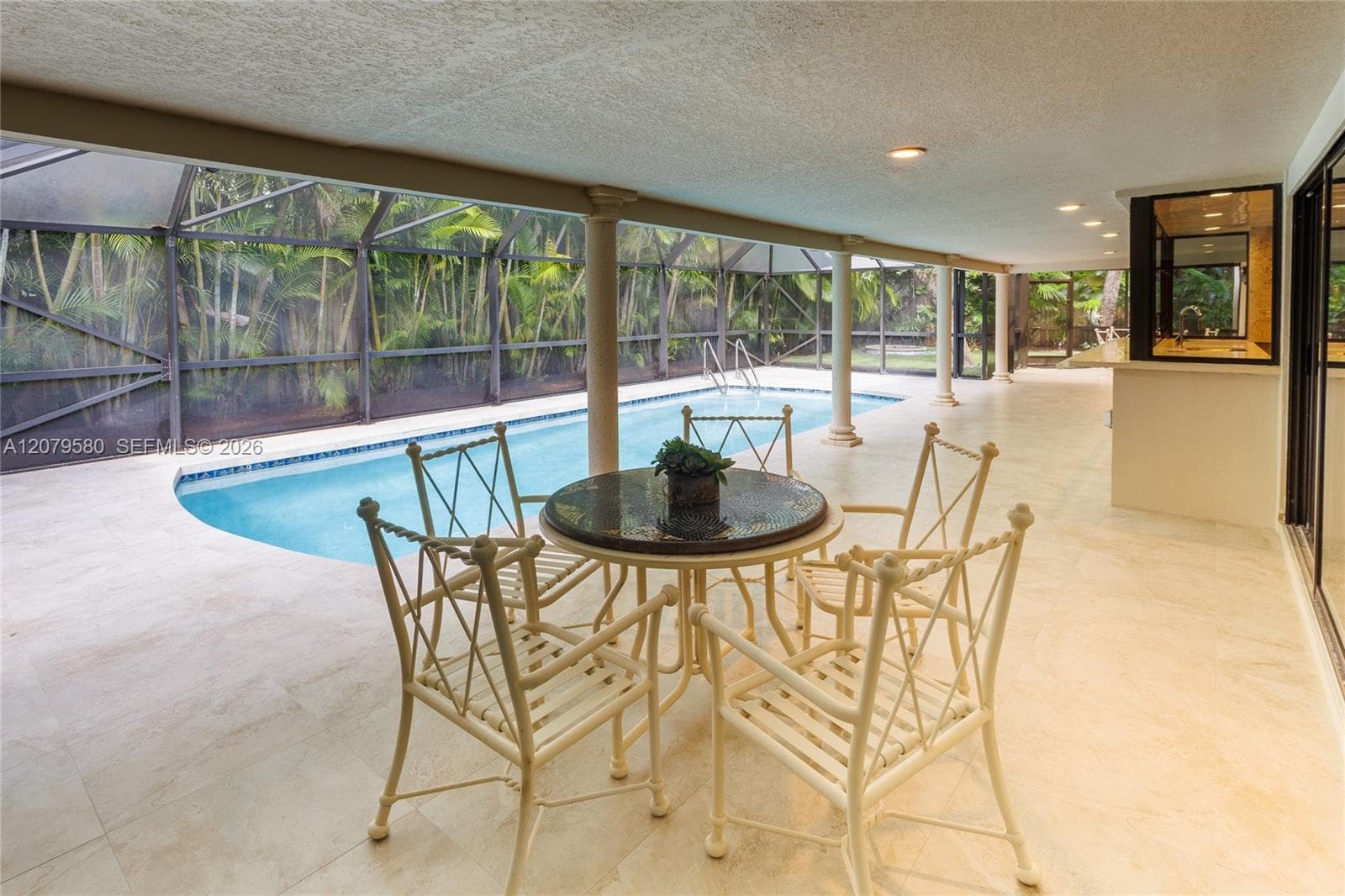Covered lanai featuring large-format tile flooring, recessed lighting, a built-in outdoor bar, and a screened enclosure surrounding a pool