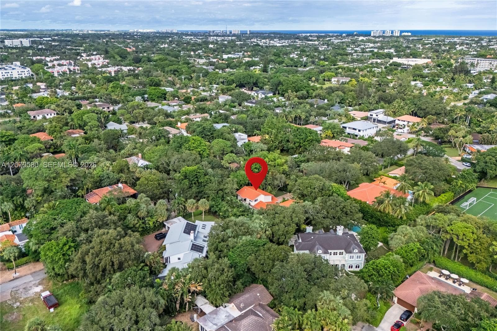Aerial perspective featuring a residential lot with mature canopy trees, proximity to coastal waters, and extensive surrounding vegetation