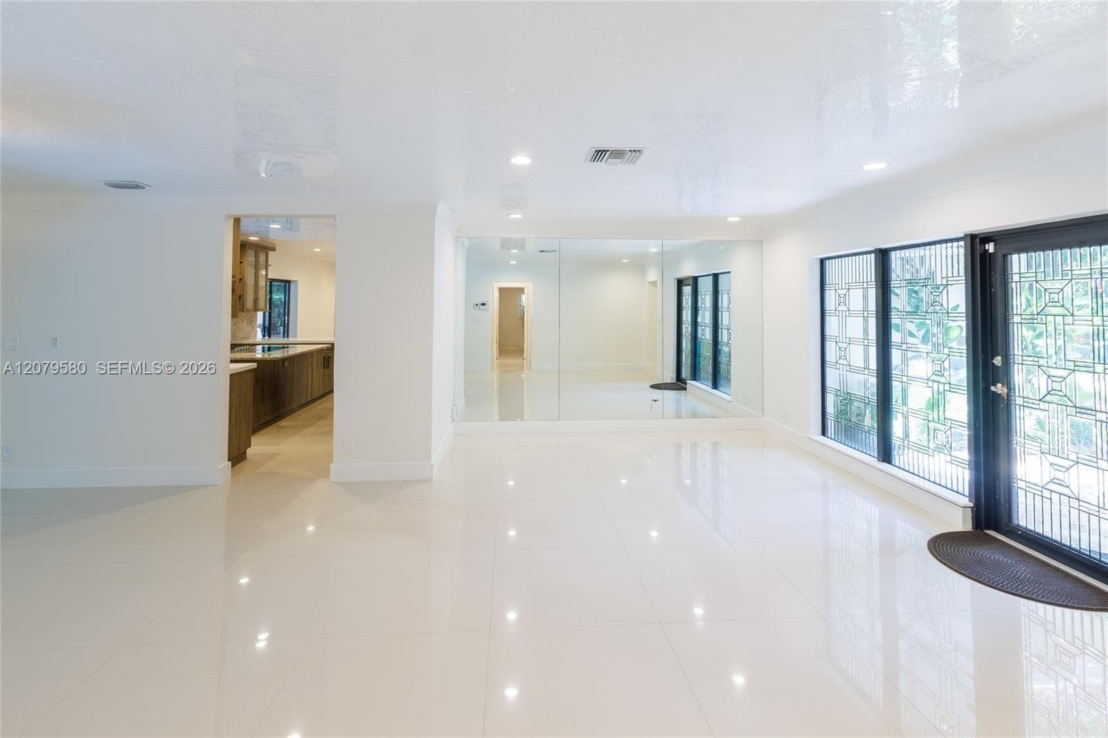 Polished tile flooring, recessed lighting, expansive mirrored wall, and decorative glass-paneled exterior door