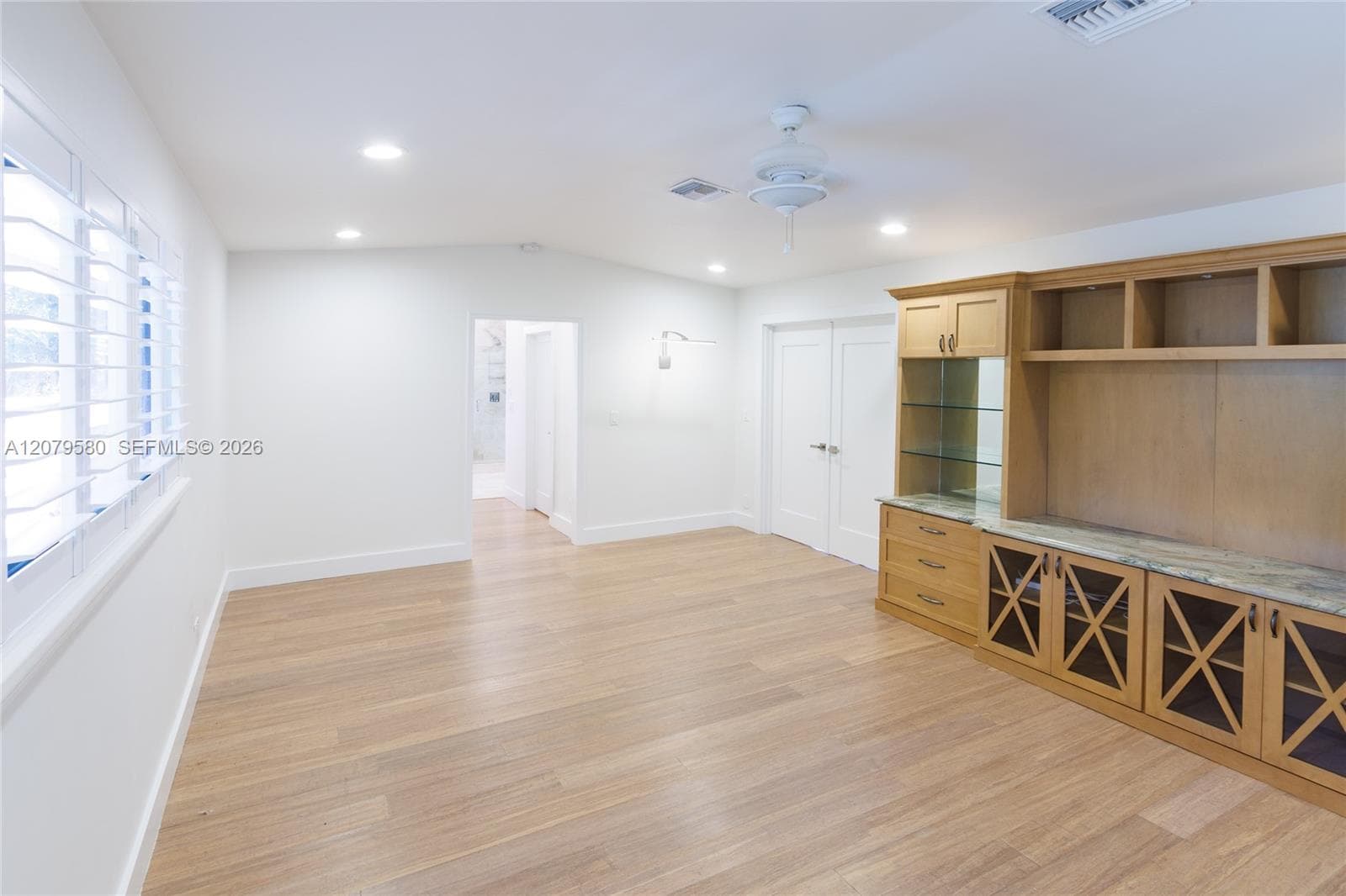 Interior space featuring wood-finish flooring, built-in cabinetry with glass shelving and stone countertops, recessed lighting, and a ceiling fan