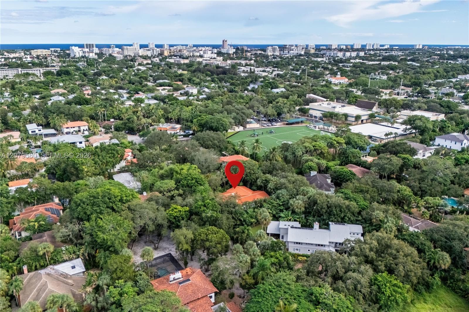 Aerial perspective featuring a terracotta tile roof and mature tree canopy within a dense urban landscape