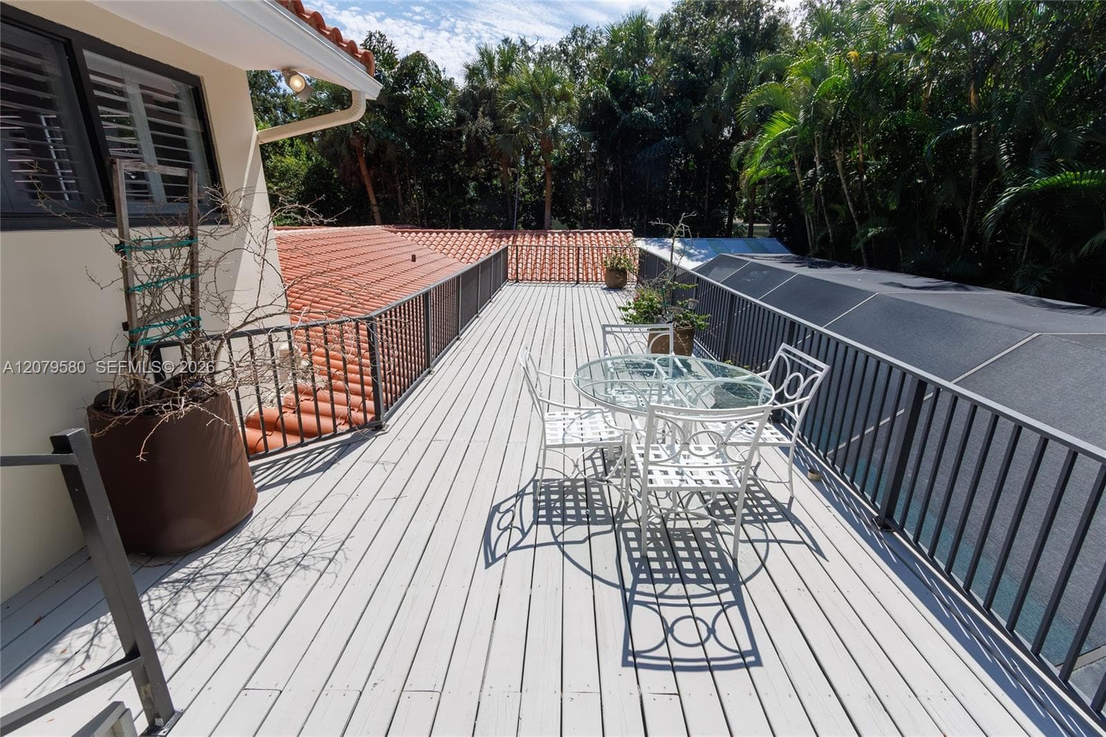Expansive upper-level deck featuring composite decking, full-length metal railings, and terracotta roof tile accents