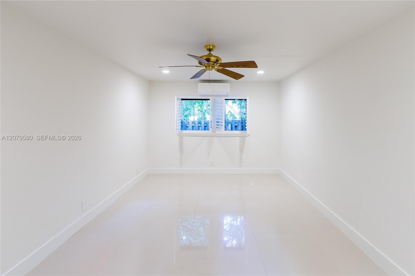 Interior space featuring light-toned tile flooring, recessed lighting, a ceiling fan with a metallic finish, shutter-style window coverings, and a wall-mounted climate control unit