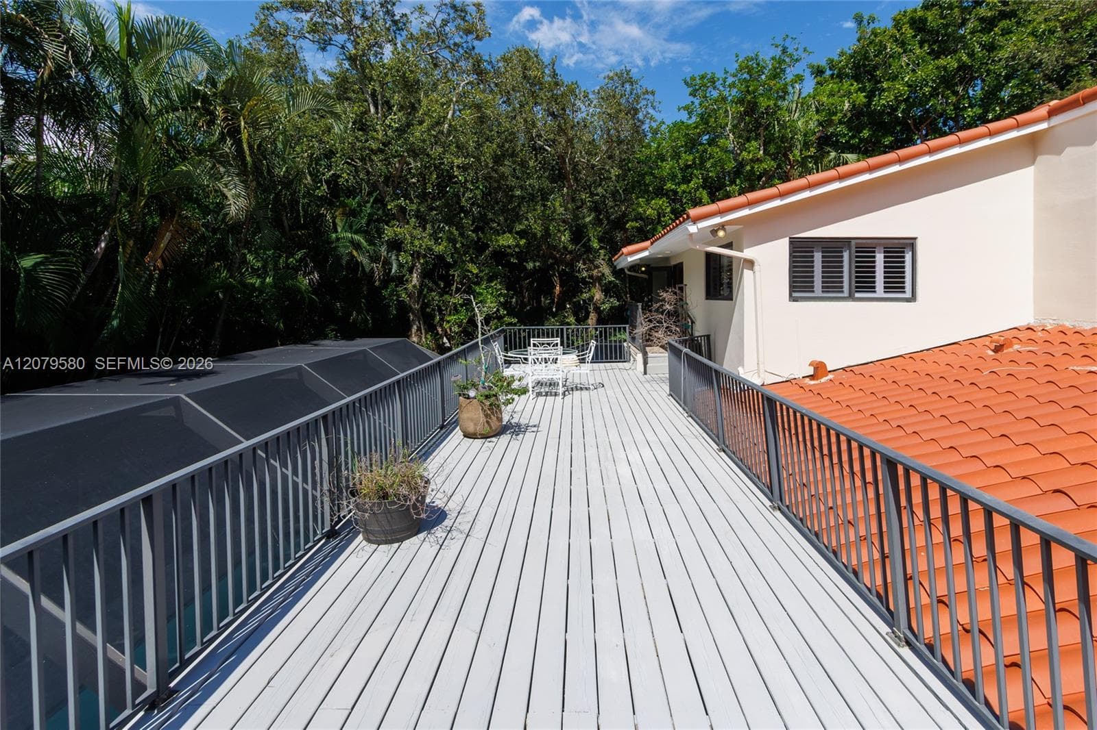 Elevated deck featuring light-toned composite decking, metal railings, and a terracotta-style tile roof