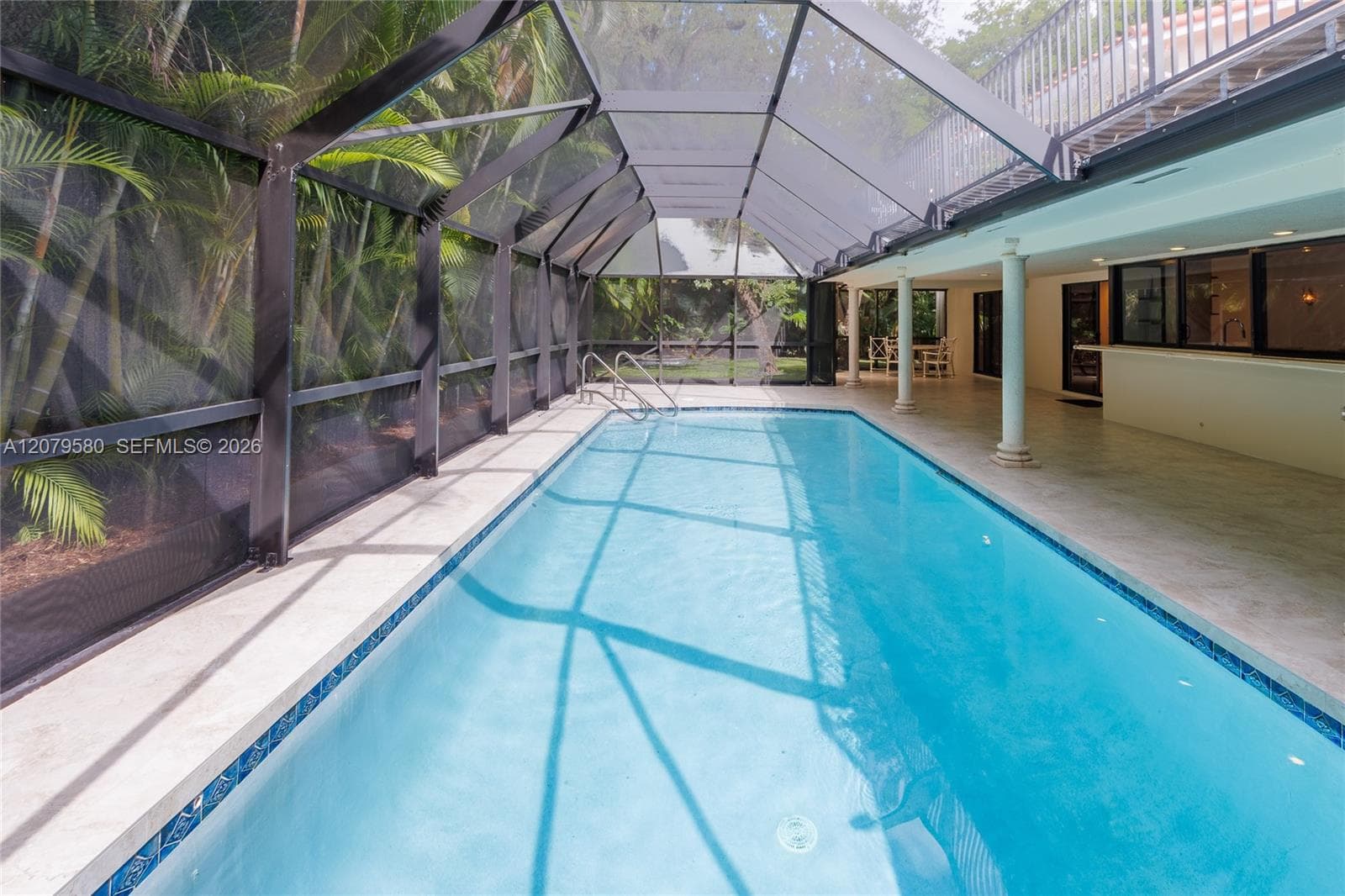 Screen-enclosed pool featuring tile coping, metal structural framing, tiled pool deck, and integrated columns