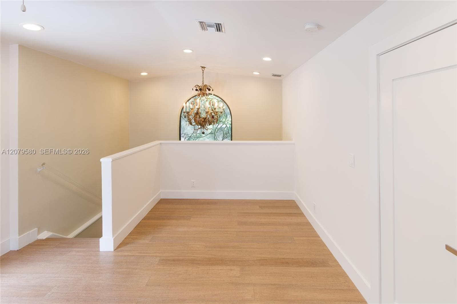 Wood-finish flooring, recessed lighting, arch-top window, and ornate chandelier