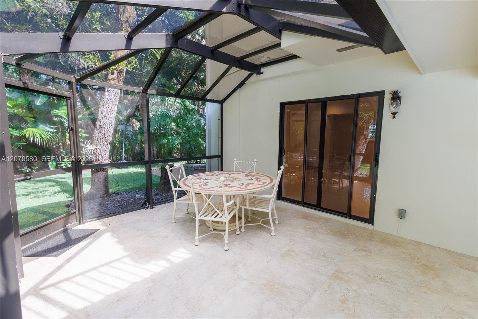 Screened-in patio featuring a geometric metal frame, light stone-finish tile flooring, and glass sliding doors